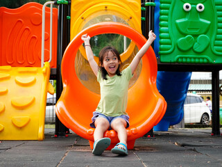 Children playing in the playground during summer vacation. Cute girl having fun on a colorful slide...