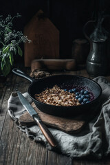 Dark Moody Kitchen Scene with Rustic Wooden Table, Cast Iron Skillet of Roasted Nuts, Vintage Kettle, and Fresh Herbs in Dramatic Chiaroscuro Lighting






