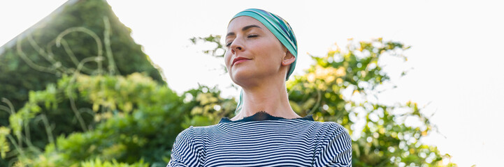 Beautiful young positive female cancer patient wearing headsacrf outdoors garden portrait. Mental...