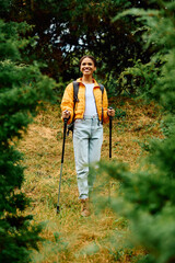 A young woman enjoys her hike in a lush autumn forest filled with colorful foliage and natural beauty.