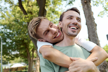 Fototapeta premium Two happy individuals embrace warmly under the bright sun among lush greenery.