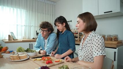 Happy father move to music while cooking food and prepare lunch at modern kitchen. Active dad dancing to song while making healthy food or salad surrounded with vegetable and kitchenware. Pedagogy.