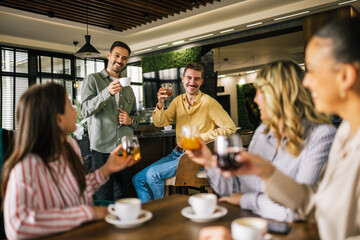 Group of female friends drinking coffee at the restaurant while the guys in the back try to flirt...