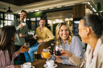 Group of female friends drinking coffee at the restaurant while the guys in the back try to flirt and send them drinks. Girl giggle and gossip about them.