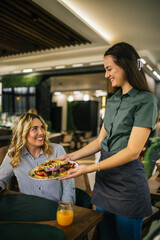 Waitress bringing in the main course for her customer.