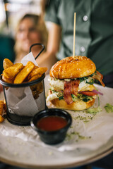 Delicious looking burger with fries and ketchup being served in a restaurant.
