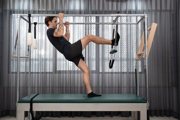 Caucasian men training pilates with pilates equipment in fitness studio	