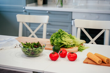 Full bowl of fresh green salad close up on a light table on a kitchen. Concept helpful and healthy food