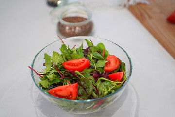 Full bowl of fresh green salad close up on a light table on a kitchen. Concept helpful and healthy food