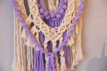 decorative wall macrame design in purple and beige colors. The intricate knots and fringes add a unique touch to the bright living space