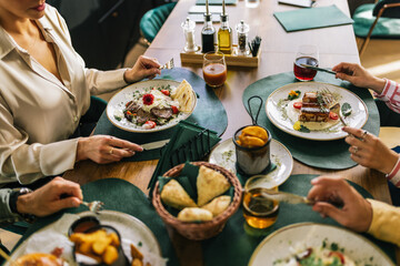 Group of happy friends eating lunch together in a restaurant. They eat delicious salads,...
