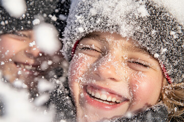A young girl is smiling and laughing while playing in the snow
