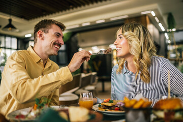Cute couple feeding each other in a restaurant.