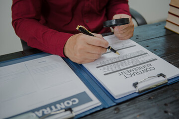 An Asian male lawyer meticulously reviews legal documents, ensuring accuracy and compliance for an...