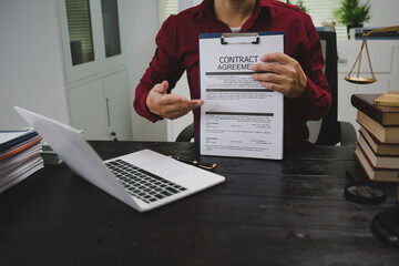 An Asian male lawyer meticulously reviews legal documents, ensuring accuracy and compliance for an...