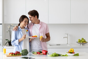 Couple in the kitchen having fun cooking vegetable breakfast, enjoying time together. Positive vegans