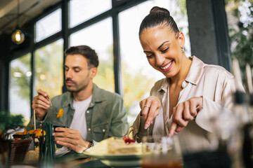 Beautiful woman eats lunch with her friends in a restaurant. She eats meat with salad.