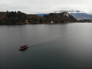 A photo of a boat is floating in a lake with mountains in the background