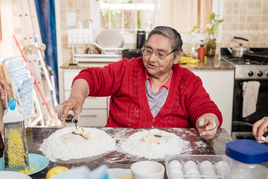 abuela cocinado galletas, alfajores y pasta frola con sus nietas