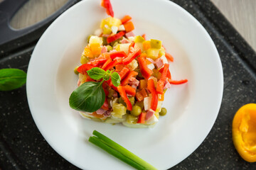vegetable salad of boiled vegetables, with peas, sausage, sweet pepper. On a wooden table