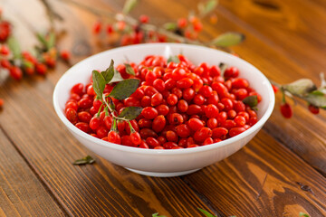 fresh ripe red goji berries in a bowl on a wooden table