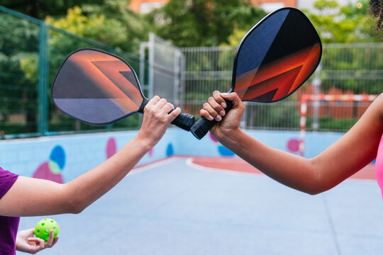 Two women holding pickleball rackets on court, ready for a match