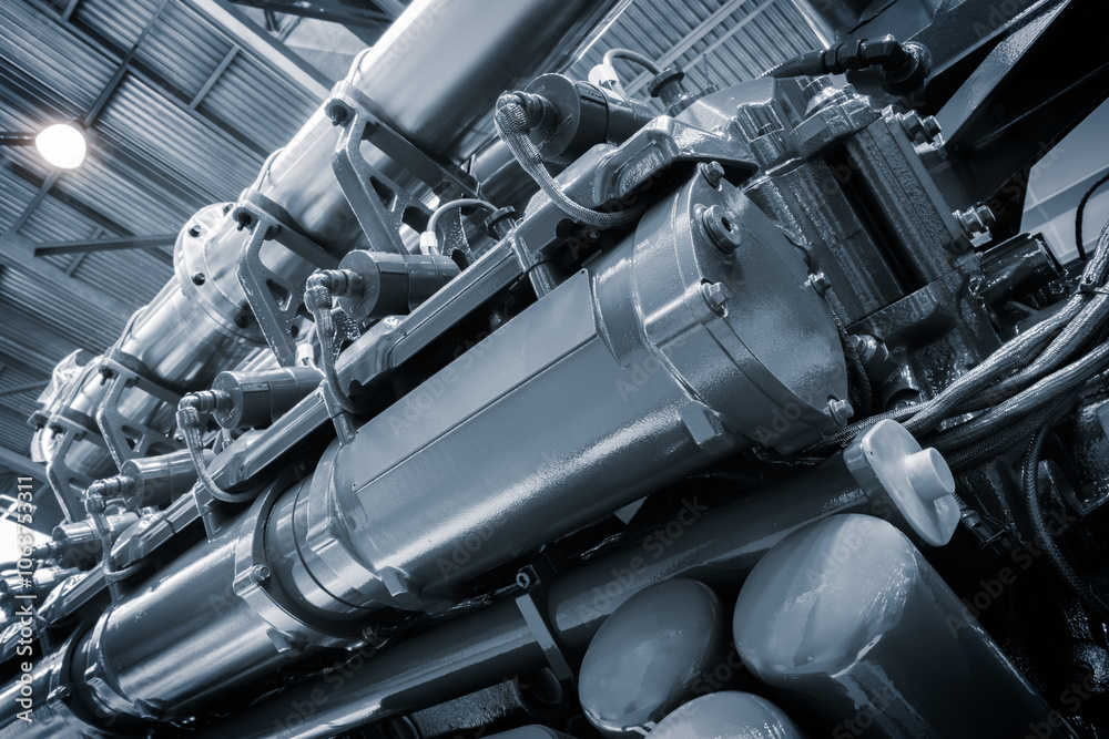 Poster A large engine with many parts is shown in a factory. The engine is made of metal and has a lot of pipes and valves. Concept of industrialization and the complexity of machinery