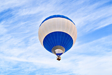 Colorful hot air balloon flying over blue sky with white clouds	