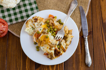 fried omelette with cauliflower and vegetables in a plate on a wooden table