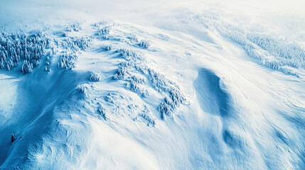 Obraz premium Aerial view of a snowy mountain range during a snowstorm with untouched snow fields