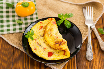 fried omelette with sweet pepper and vegetables in a plate on a wooden table