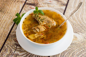 hot cooked chicken and noodle soup in a plate on a wooden table