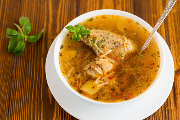 hot cooked chicken and noodle soup in a plate on a wooden table