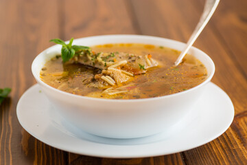 hot cooked chicken and noodle soup in a plate on a wooden table