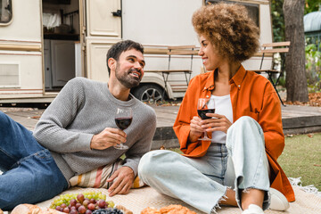 Dating and love concept. Interracial young couple traveling on holidays, drinking red wine,...