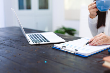 An Asian woman sits at her desk, surrounded by files  , embodying dedication and professionalism in her work.