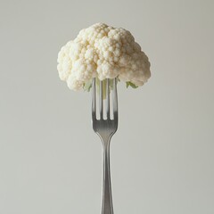 Fresh cauliflower head on elegant fork against neutral background for healthy eating concept