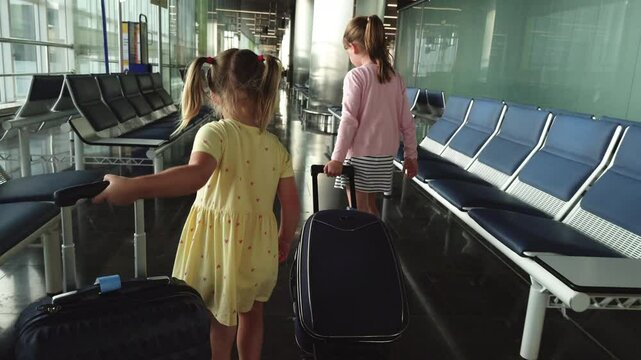4K: Two young girls at the Airport pulling luggage or suitcases through the terminal before boarding. Stock Video Clip Footage