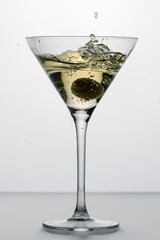 splash in a glass of dry martini with green olive, alcohol, cocktail, bar