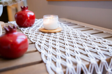 Cozy indoor scene with a lit candle, decorative pottery, and knitted table runner