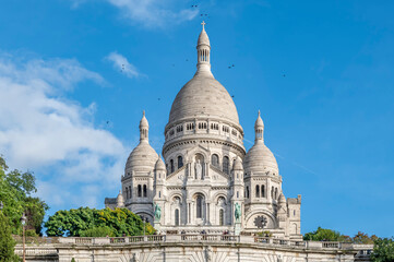 The ancient Basilica of the Sacred Heart in Montmartre, Paris, France, with black birds flying near...