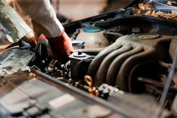 Fototapeta premium Mechanic Working on Car Engine in Dimly Lit Garage