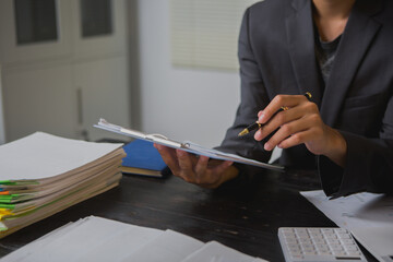 An Asian man works late at his desk papers, determined to meet his deadlines.