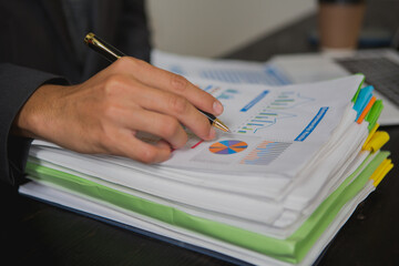 An Asian man works late at his desk papers, determined to meet his deadlines.