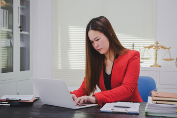 Asian businesswoman, focused , sits at ablack wooden table. Surrounded by notes , she strategizes her next move, embodying confidence and professionalism in her workspace.