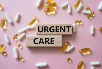 Urgent Care symbol. Concept word Urgent Care on wooden blocks. Beautiful pink background with pills. Medicine and Urgent Care concept. Copy space