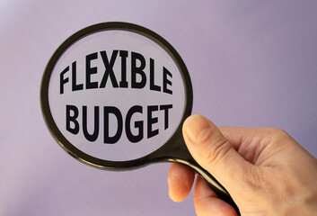 Flexible budget symbol. Concept words Flexible budget on magnifying glass. Beautiful purple background. Businessman hand. Business and Flexible budget concept. Copy space.