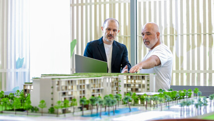 A manager consults with a client near a detailed model of a multi-story building, discussing...