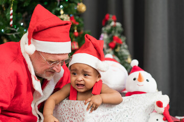 Santa Claus calming crying African child while playing together