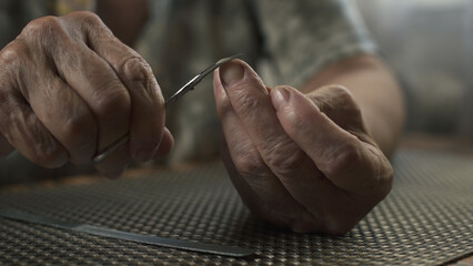 Obraz premium Elderly woman cutting her nails. Hands close-up.